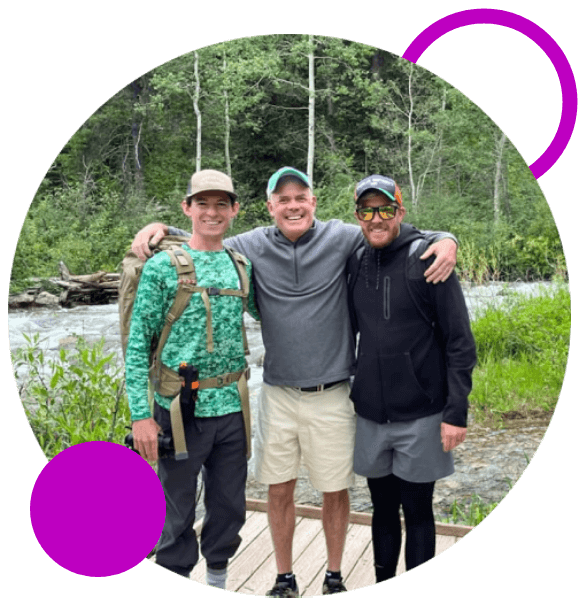 Three men standing next to each other on a bridge.